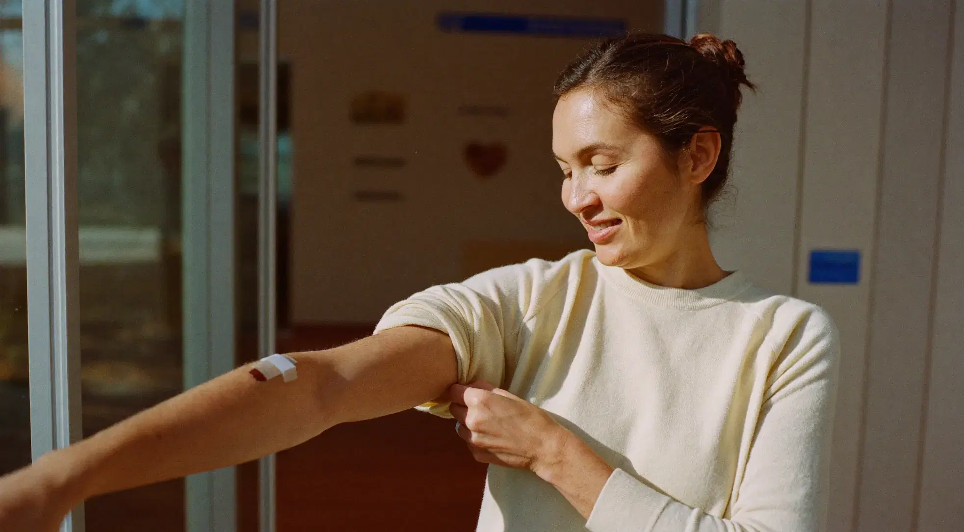 Woman rolling down her sleeve over a small bandage after a blood draw