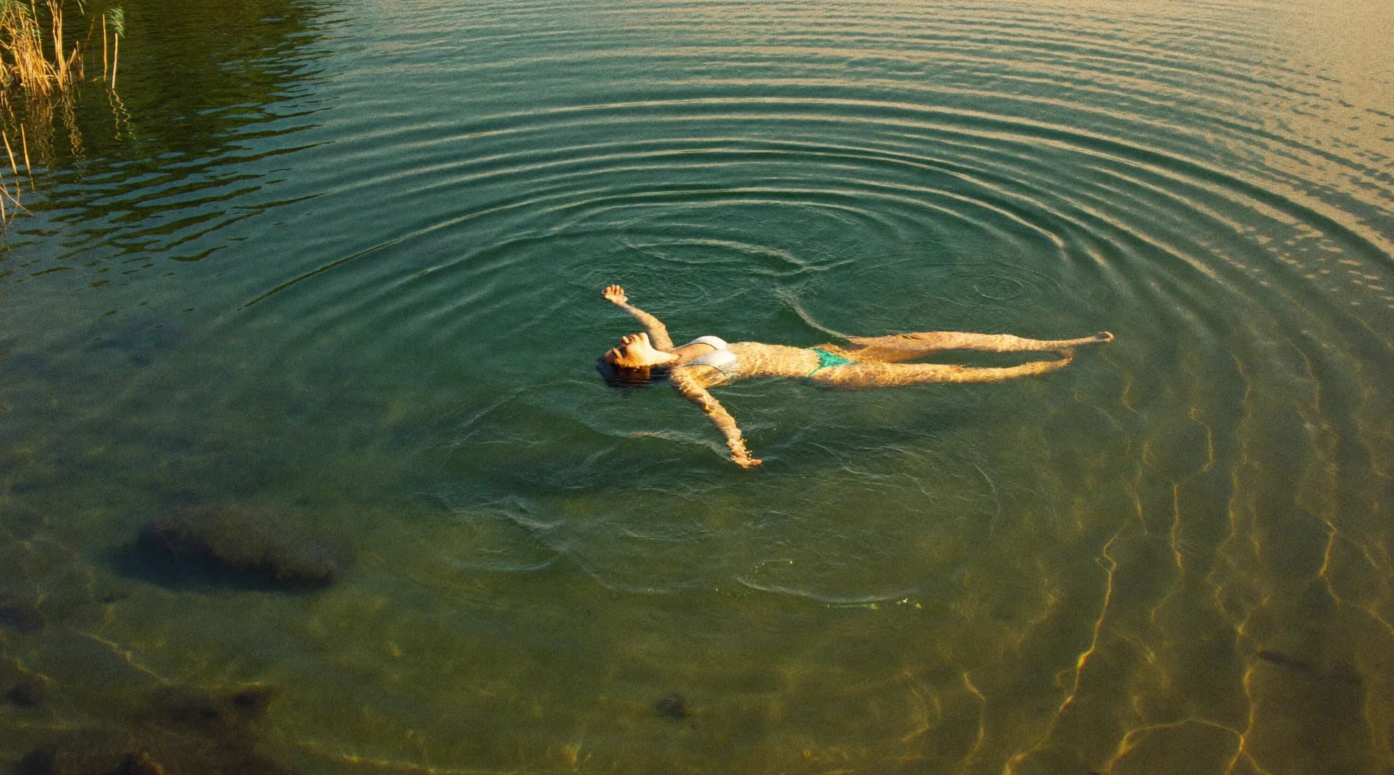 Woman floating on a calm lake in late light