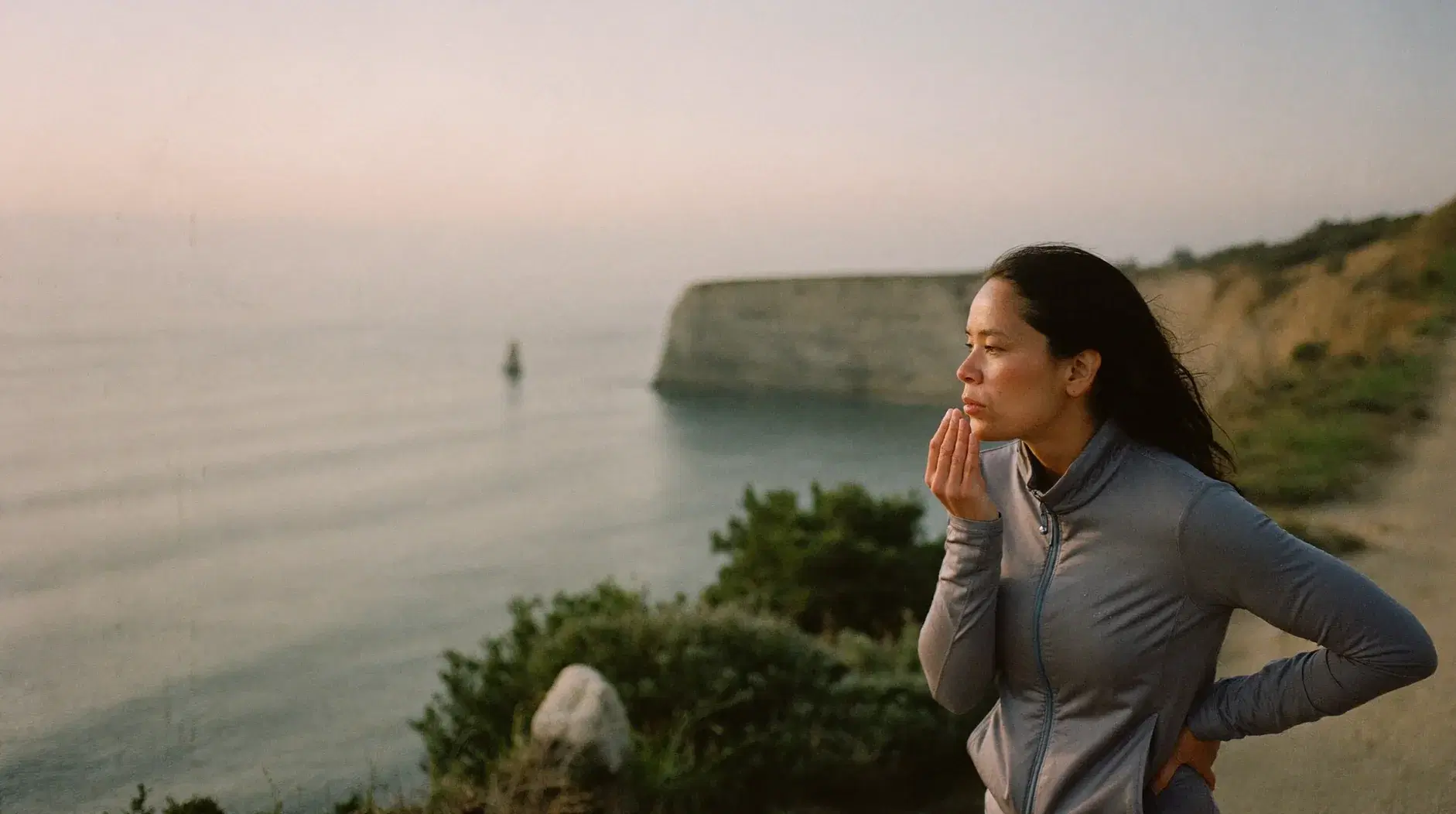 Woman catching her breath on a coastal path after a morning run