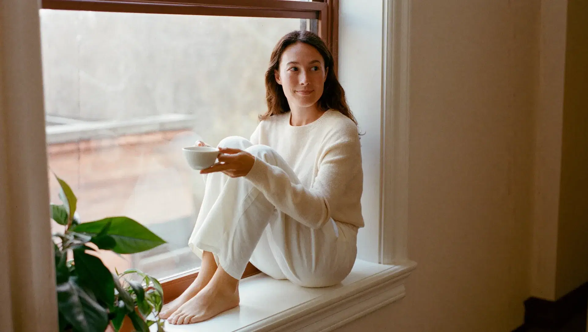 Woman with a cup of tea on a sunny window sill